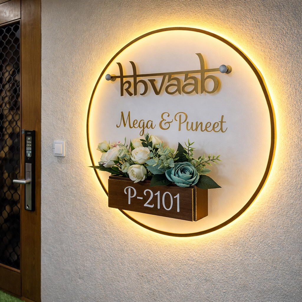 Round LED acrylic floral pot nameplate with warm backlight mounted on a modern apartment flat entrance wall beside a wooden door, showing custom house name and number.
